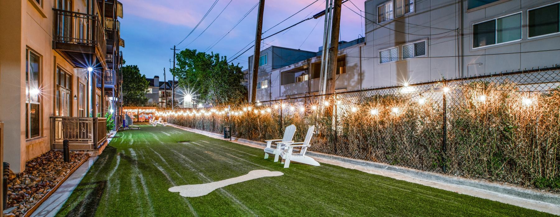 a yard with a chair and a building with lights on it